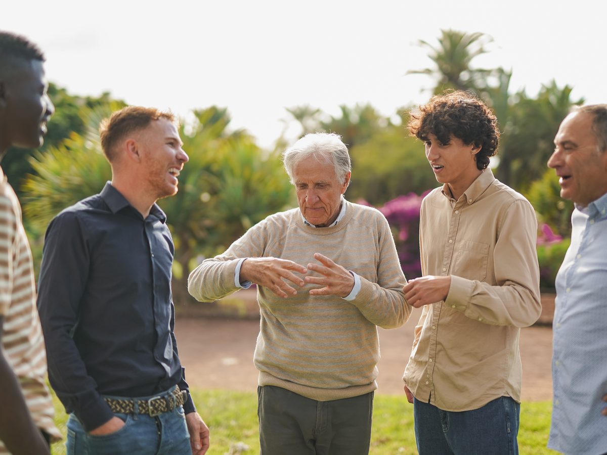 Multi-generational men talking together on a city street, casual and unhurried.