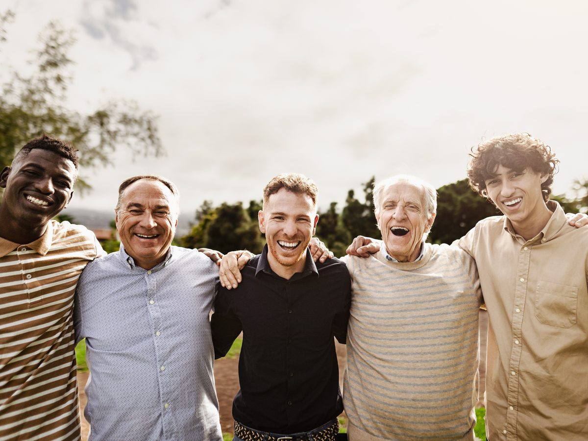 A multigenerational group of men, smiling and at ease in each other's company.