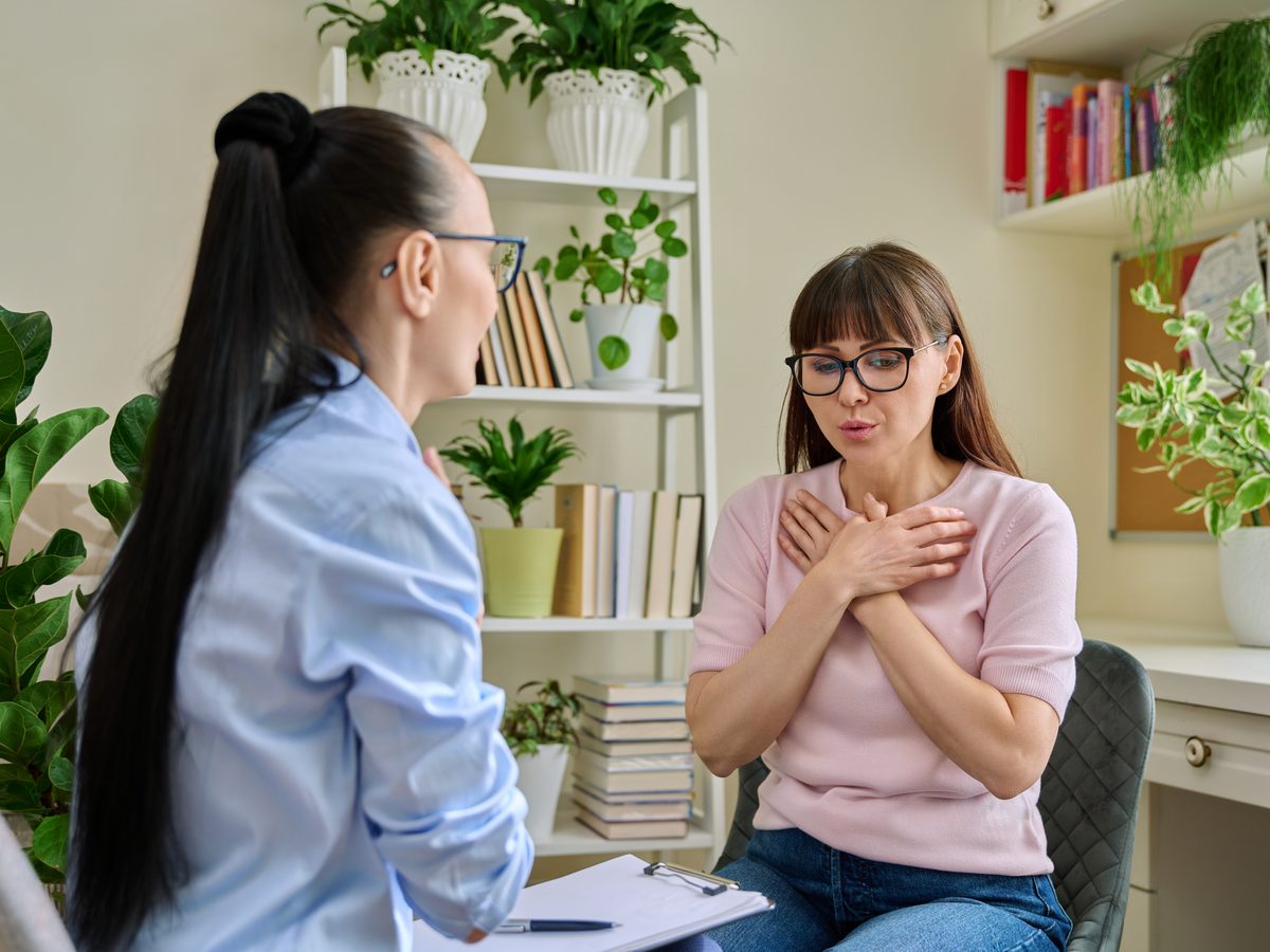 A person in conversation with a healthcare professional, hands gesturing in description.